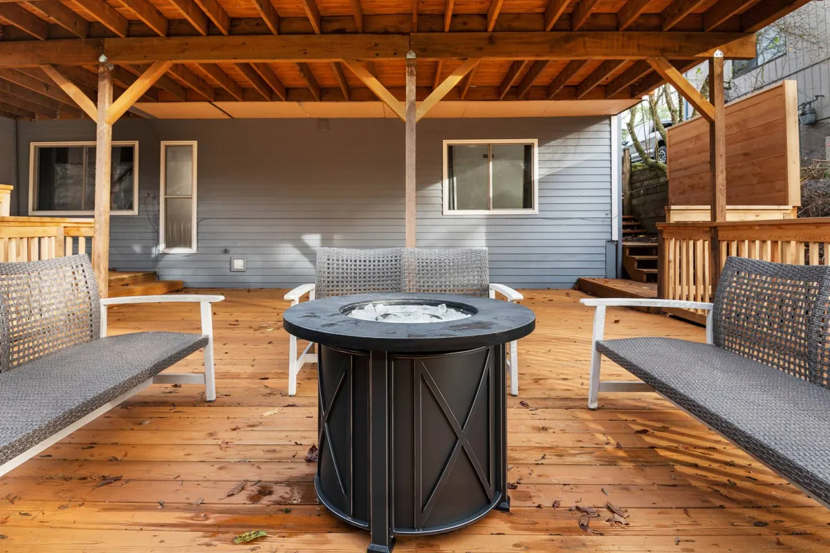 This exterior image showcases a cozy outdoor fire pit area surrounded by comfortable seating and wooden beams, creating an inviting atmosphere for guests to gather in the evening. The warm lighting emphasizes the space's suitability for conversations, laughter, and shared meals under the stars.